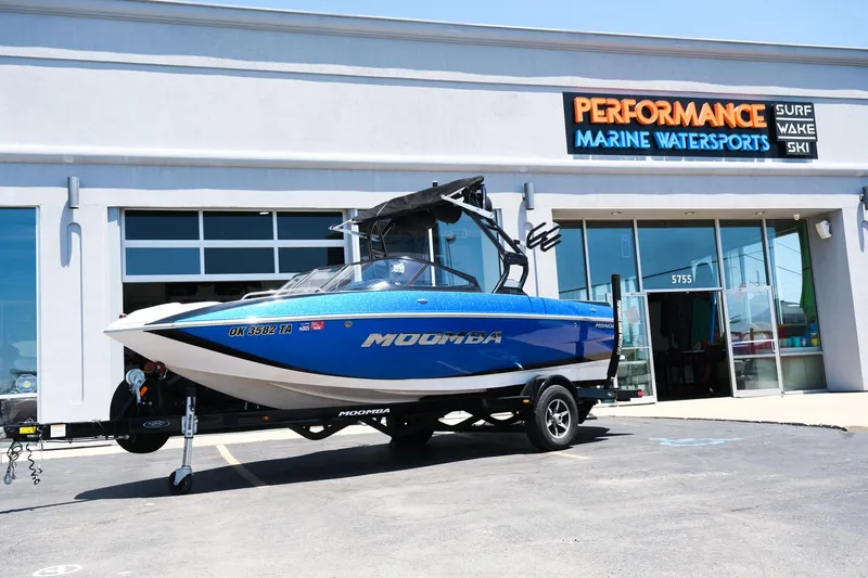 Slide: The Image of 2017 Moomba Mondo boat in blue, parked outside Performance Marine Watersports dealership. - 1