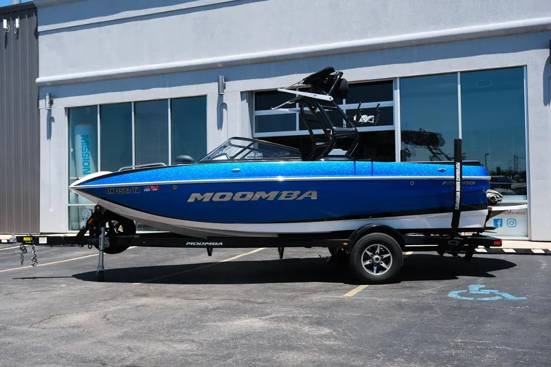 Slide: The Image of 2017 Moomba Mondo boat in blue, parked on a trailer outside a building. - 2