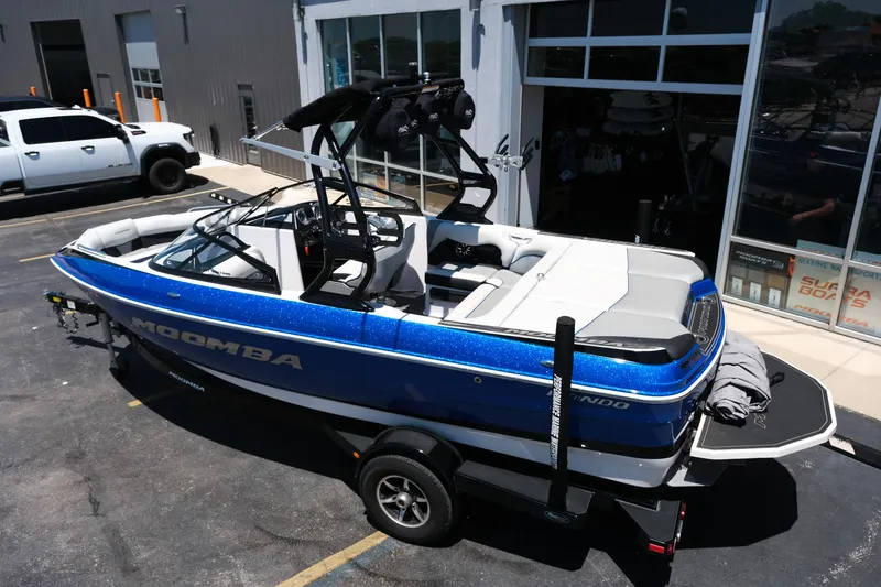 Slide: The Image of 2017 Moomba Mondo boat in blue, parked on a trailer outside a building. - 3