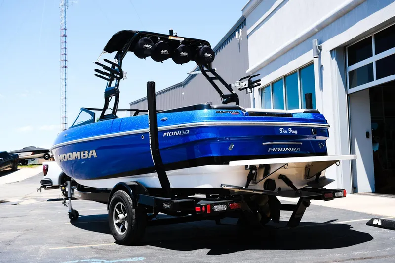 Slide: The Image of 2017 Moomba Mondo boat in blue, parked on a trailer outside a building. - 4