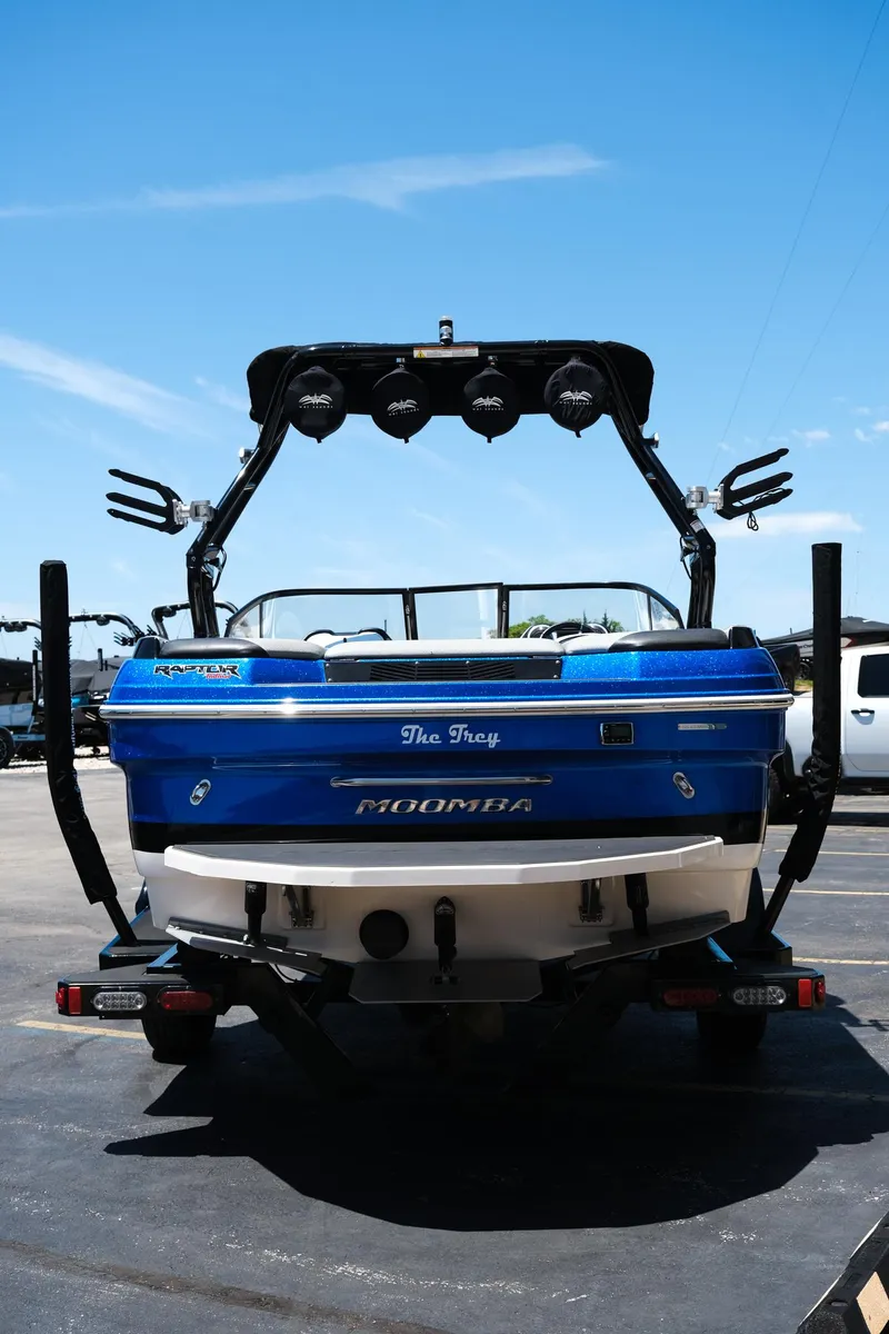 Slide: The Image of 2017 Moomba Mondo boat, blue exterior, parked on pavement under clear sky. - 5
