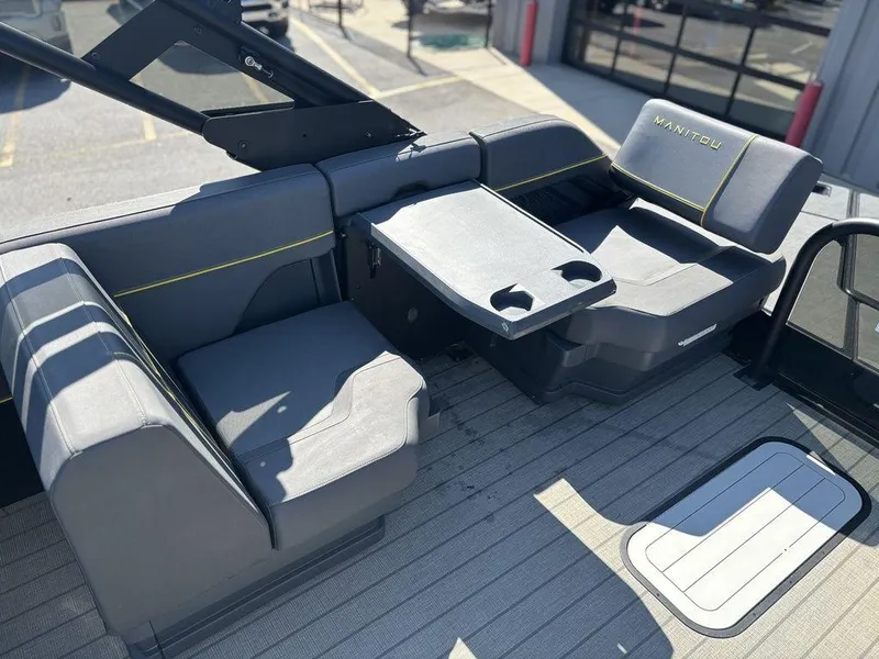 Slide: The Image of 2023 Manitou Explore 22 Max Bench boat interior with gray seating and table. - 2