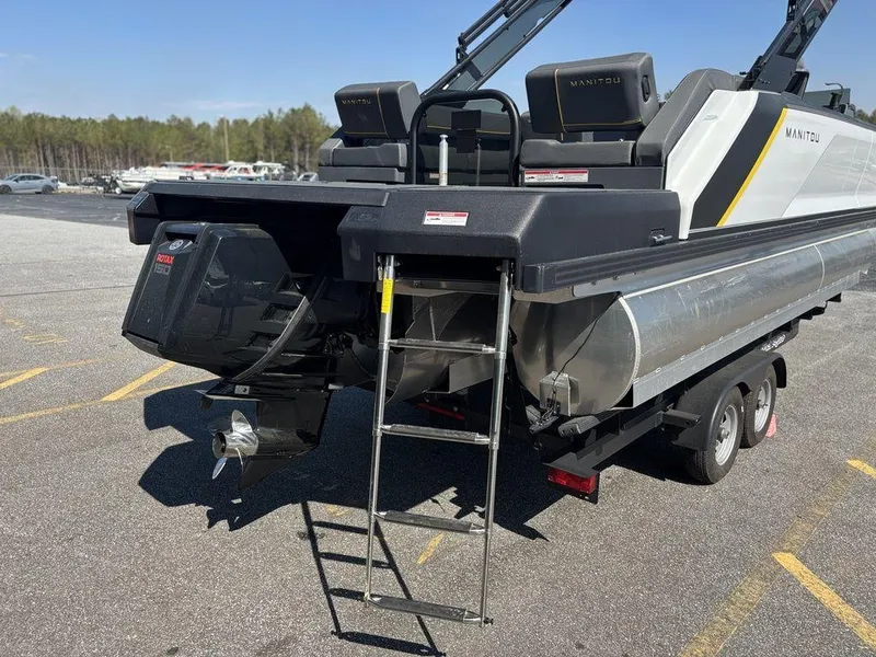 Slide: The Image of 2023 Manitou Explore 22 Max Bench pontoon boat with ladder and motor, parked on trailer. - 21