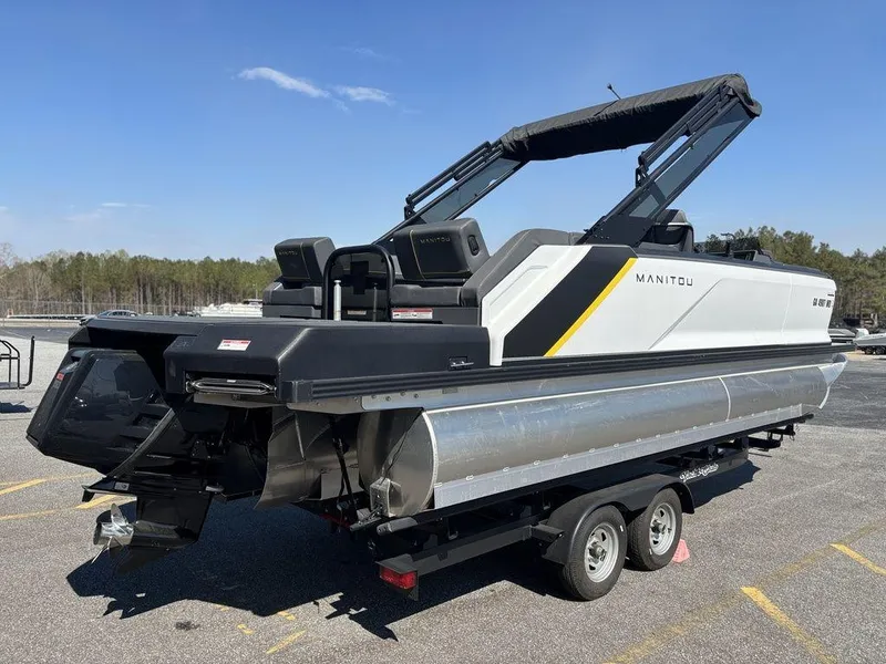 Slide: The Image of 2023 Manitou Explore 22 Max Bench pontoon boat on trailer, parked outdoors. - 22