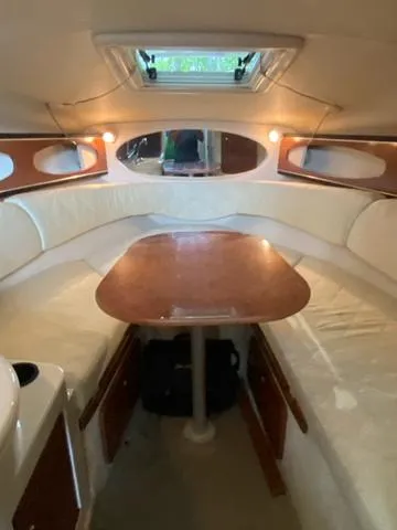 Slide: The Image of 2004 Sea Ray 260 Sundancer cabin interior with table and seating, featuring wood accents and lighting. - 14