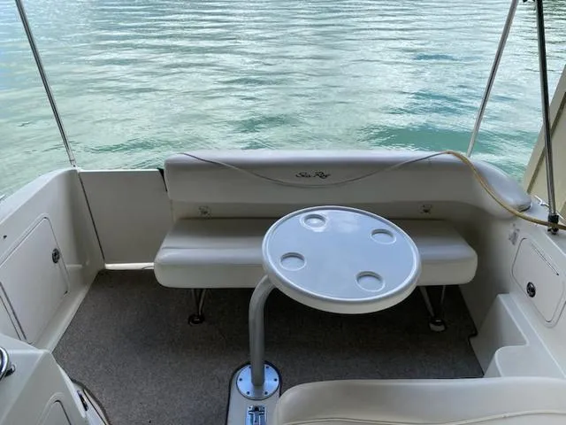 Slide: The Image of 2004 Sea Ray 260 Sundancer boat interior with seating and table, overlooking calm water. - 2
