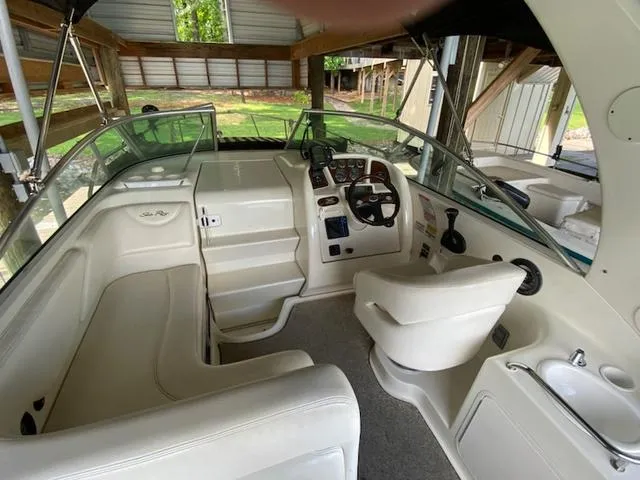 Slide: The Image of 2004 Sea Ray 260 Sundancer boat interior with helm, seating, and controls in a covered dock. - 7