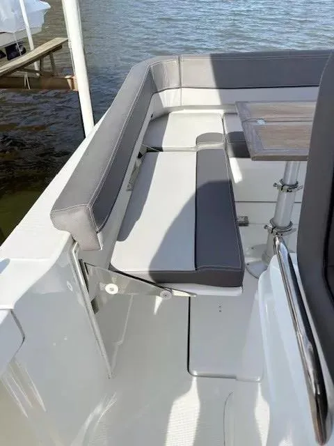 Slide: The Image of 2020 Jeanneau Leader 9.0 CC boat seating area with table, docked by water. - 11