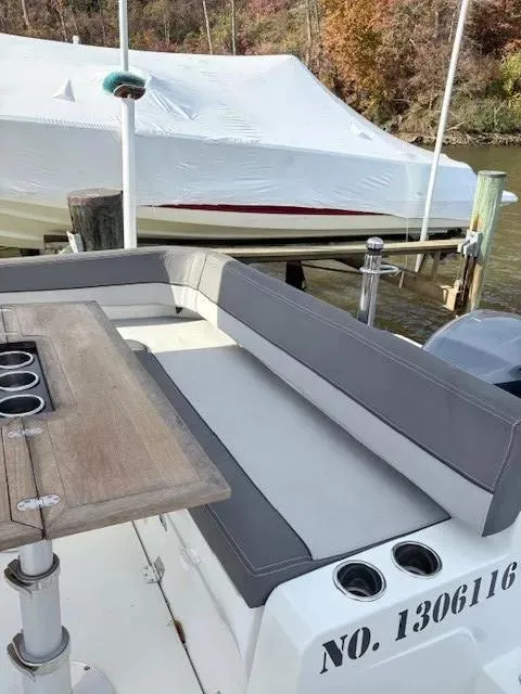 Slide: The Image of 2020 Jeanneau Leader 9.0 CC boat with cushioned seating and table, docked near covered vessel. - 13