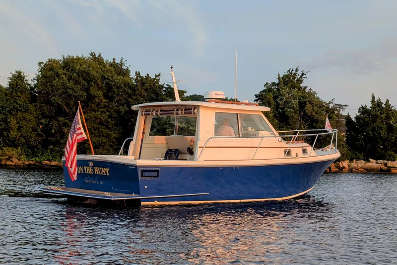 Slide: The Image of 2000 Hunt Yachts 28 Express boat on water, American flag, trees in background. - 2