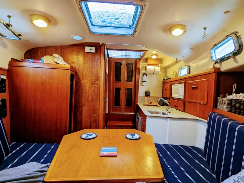 Slide: The Image of Interior of 2000 Hunt Yachts 29, featuring cozy seating and wooden cabinetry. - 26