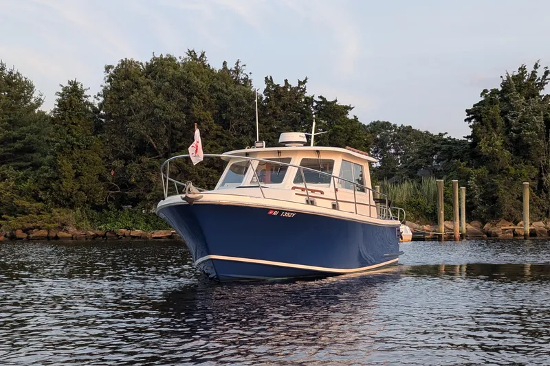 Slide: The Image of Hunt Yachts 28 Express 2000 model on calm water near a wooded shoreline. - 3
