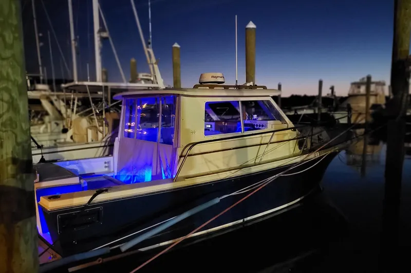 Slide: The Image of 2000 Hunt Yachts 28 Express docked at night with blue interior lighting. - 5