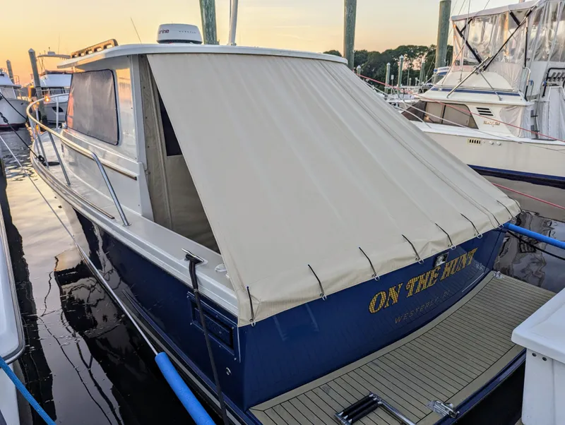 Slide: The Image of 2000 Hunt Yachts 29 docked, featuring a beige canopy and blue hull. - 8