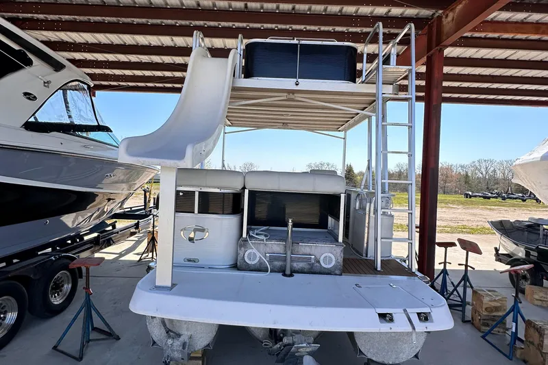 Slide: The Image of 2011 Tahoe Pontoon 2685FS Sierra Funship with slide and upper deck, stored under a metal roof. - 2