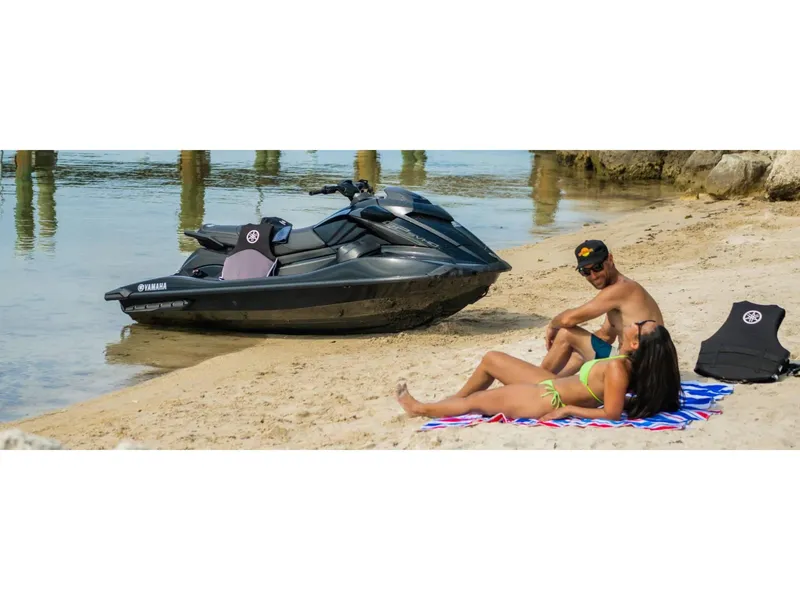 Slide: The Image of 2024 Yamaha GP SVHO jet ski on sandy beach with two people relaxing nearby. - 20
