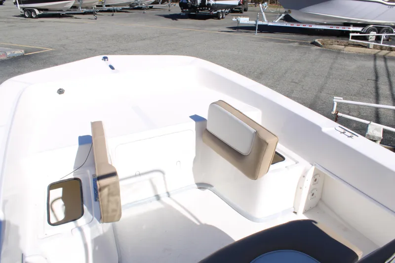 Slide: The Image of 2025 Sundance B20CCR boat interior with beige seating, parked in a marina. - 11