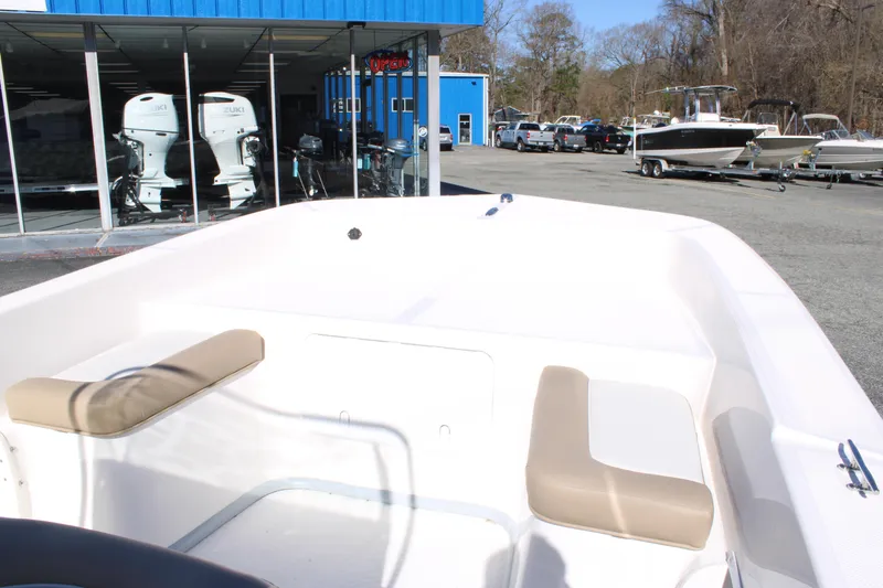 Slide: The Image of 2025 Sundance B20CCR boat interior with beige seating, displayed at a dealership. - 12