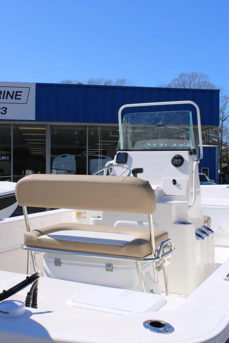 Slide: The Image of 2025 Sundance B20CCR boat with beige seating, displayed outside a marine dealership. - 6