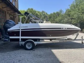 The Image of 2019 Hurricane CC19 boat on trailer, parked outdoors near trees and building. - 0