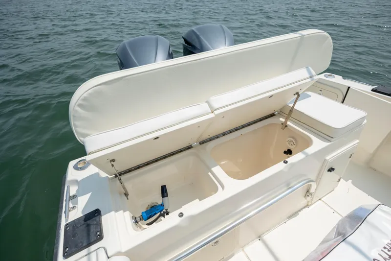 Slide: The Image of 2000 Pursuit 2470 Center Console boat with open storage compartment on calm water. - 22