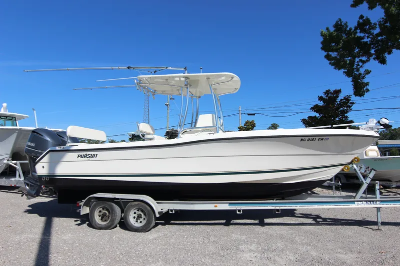 Slide: The Image of 2000 Pursuit 2470 Center Console boat on trailer, parked outdoors under clear blue sky. - 27