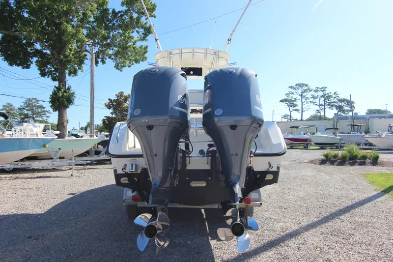 Slide: The Image of 2000 Pursuit 2470 Center Console boat with dual outboard motors, parked on gravel. - 29