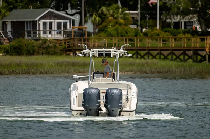 Slide: The Image of 2000 Pursuit 2470 Center Console boat cruising on a calm river near a wooden dock. - 4