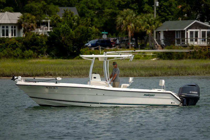 Slide: The Image of 2000 Pursuit 2470 Center Console boat on water near shoreline homes. - 7