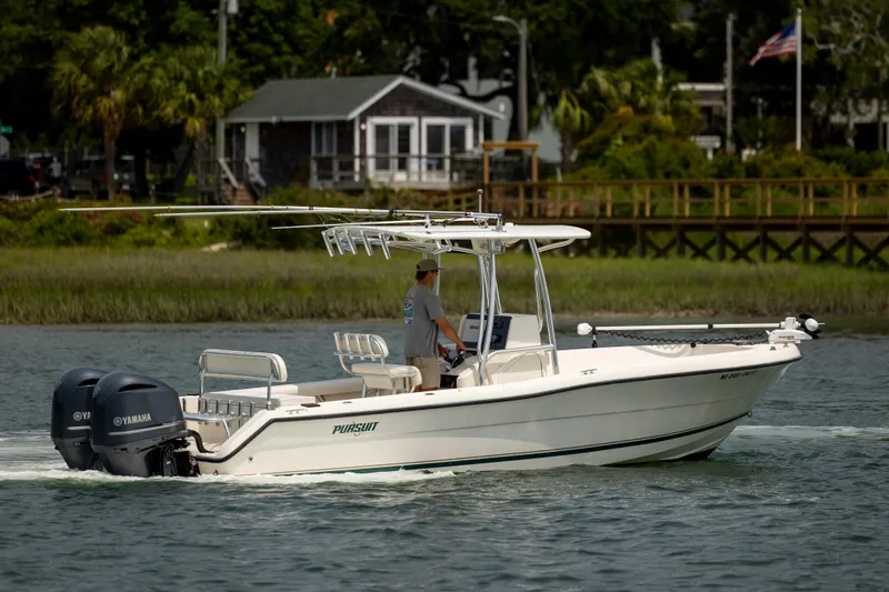 Slide: The Image of 2000 Pursuit 2470 Center Console boat cruising on a calm river with lush greenery. - 9