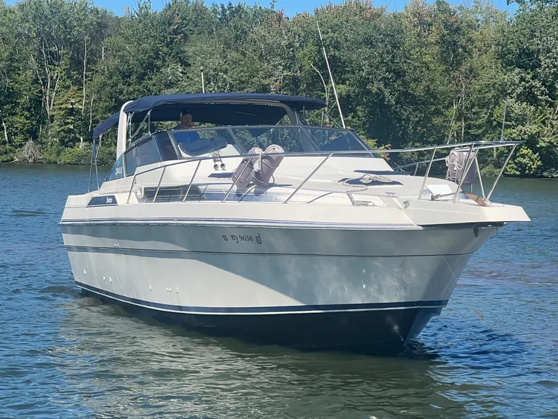 The Image of 1988 Silverton 34X Express boat cruising on a calm lake with forested background. - 0