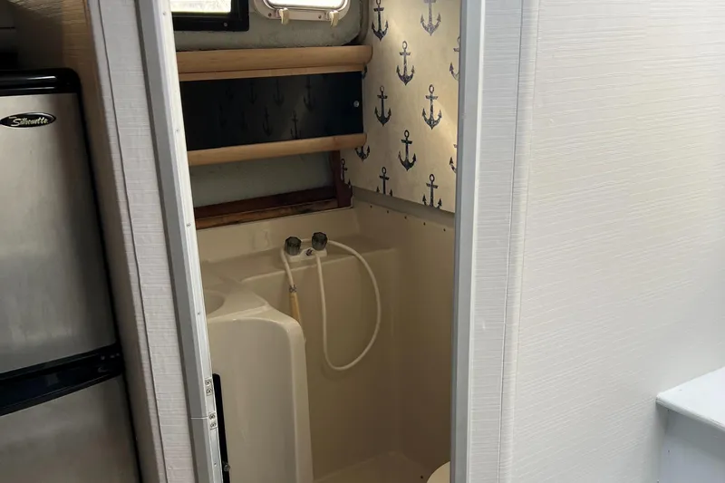 Slide: The Image of 1988 Silverton 34X Express boat bathroom with anchor-themed wallpaper and compact shower. - 20