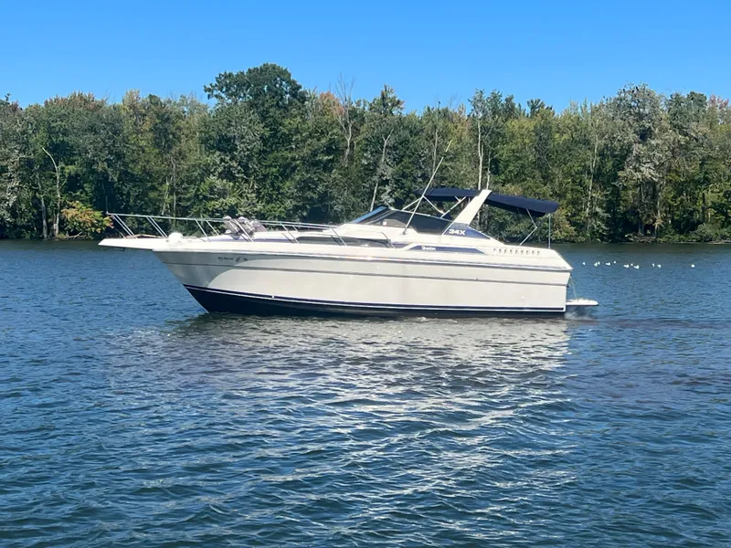 Slide: The Image of 1988 Silverton 34X Express boat on a calm lake with forested background. - 4