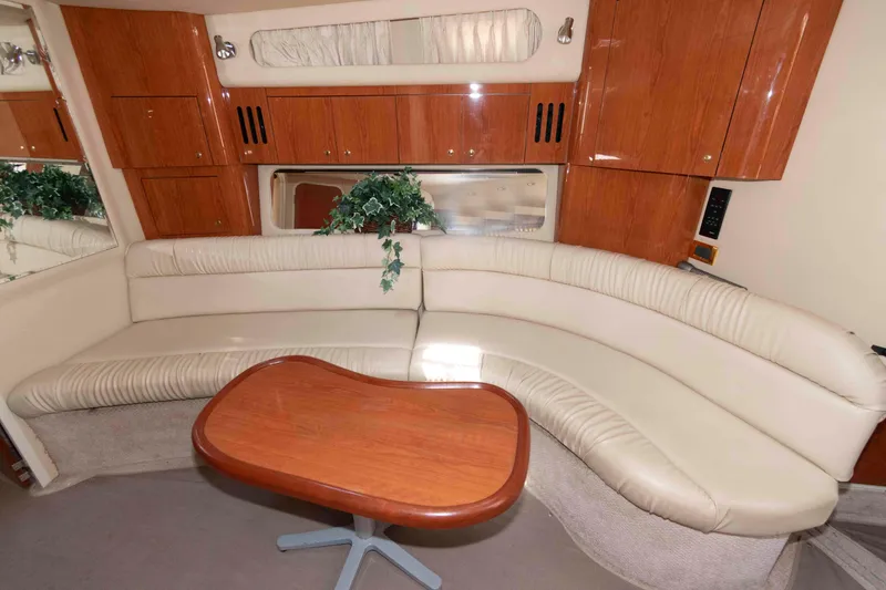 Slide: The Image of Interior of 2000 Sea Ray 410 Sundancer with curved seating and wooden table. - 11