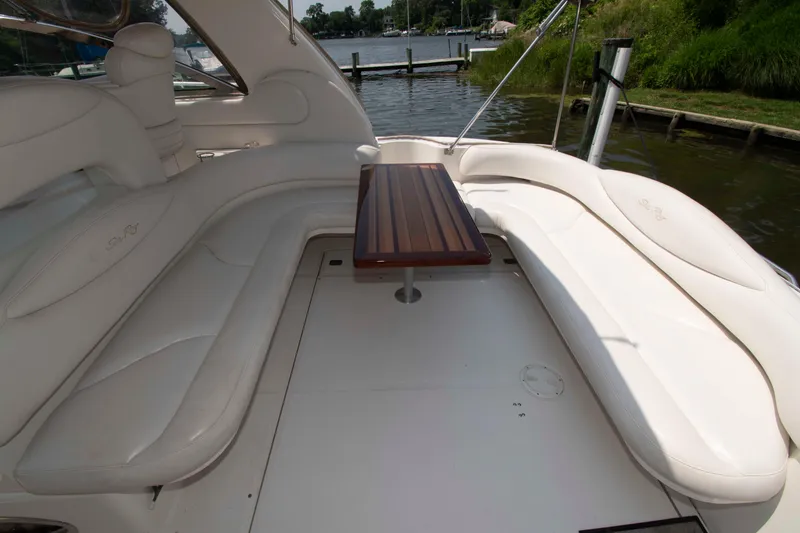 Slide: The Image of 2000 Sea Ray 410 Sundancer boat interior with white seating and wooden table. - 4