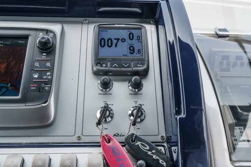 Slide: The Image of Control panel of a 2006 Riva 44 RivaRama yacht, featuring navigation instruments and branded keychains. - 39