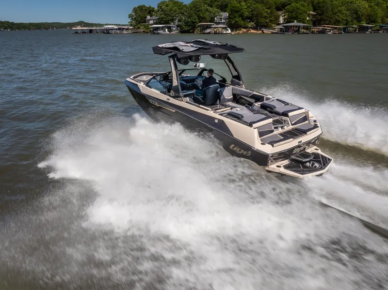 Slide: The Image of 2025 Tigé Ultré 23ZX boat cruising on a lake with lush green shoreline. - 2