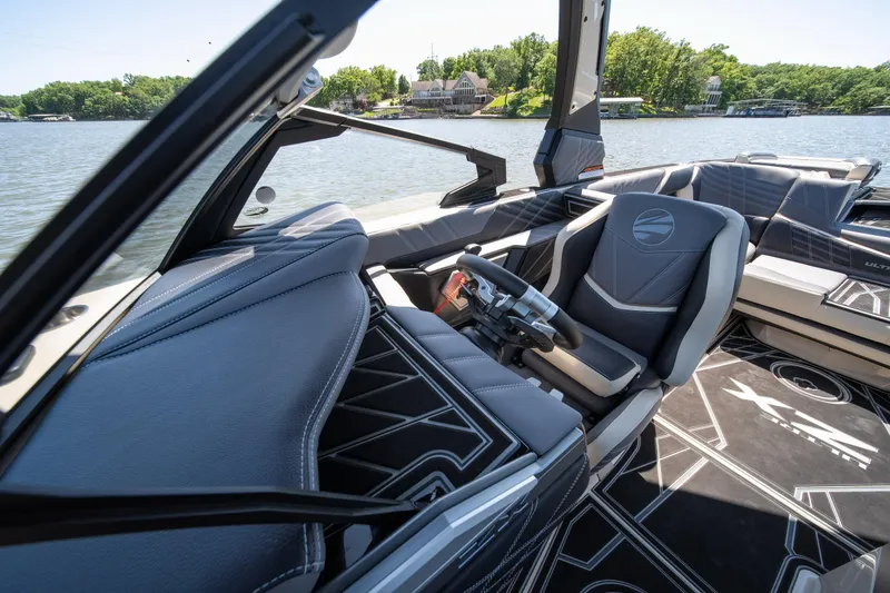 Slide: The Image of 2025 Tigé Ultré 23ZX boat interior with sleek design and modern controls on a sunny lake. - 26