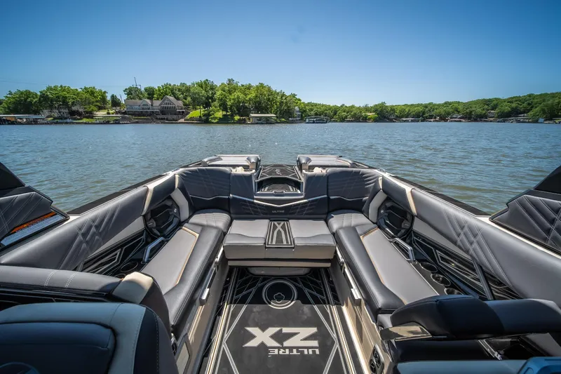 Slide: The Image of 2025 Tigé Ultré 23ZX boat interior with luxurious seating on a scenic lake. - 29
