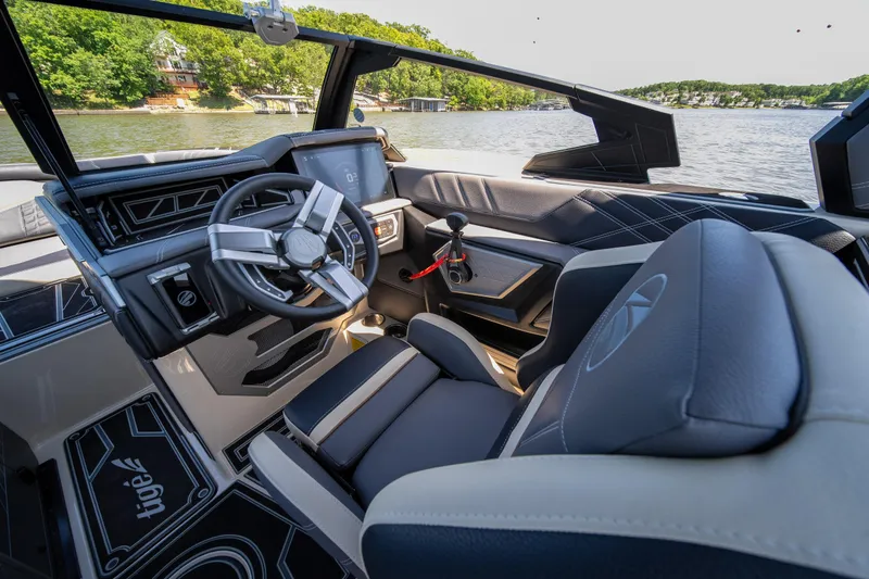 Slide: The Image of 2025 Tigé Ultré 23ZX boat interior with modern steering and dashboard, on a scenic lake. - 43