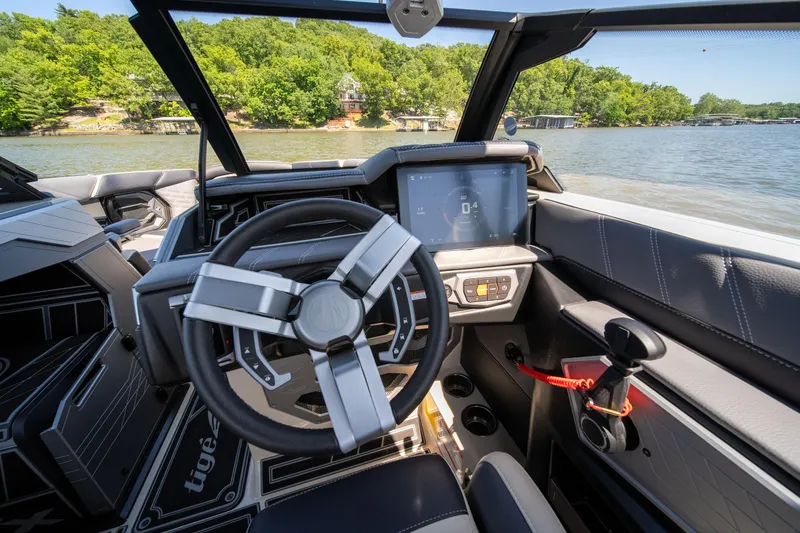 Slide: The Image of 2025 Tigé Ultré 23ZX boat interior with modern steering and control panel on a sunny lake. - 44