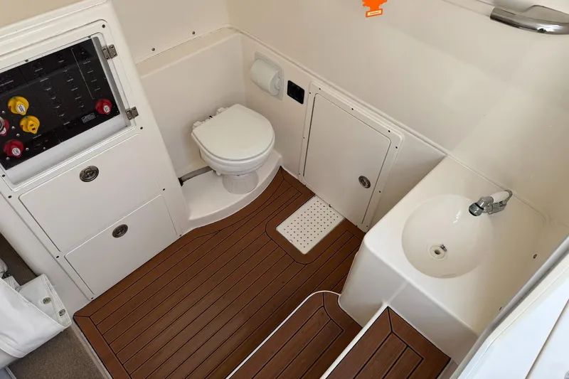Slide: The Image of 2017 Cobia 344 Center Console boat bathroom with toilet, sink, and wood-style flooring. - 13