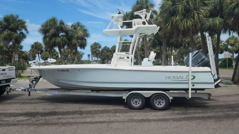 Slide: The Image of 2020 Robalo 246 Cayman boat on trailer, parked near palm trees. - 10