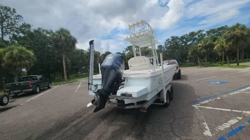 Slide: The Image of 2020 Robalo 246 Cayman boat on trailer in parking lot, surrounded by trees. - 15