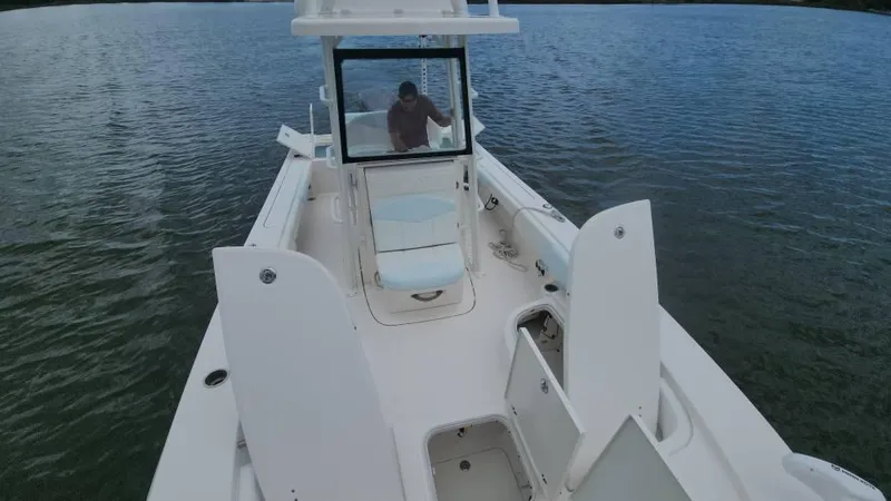 Slide: The Image of 2020 Robalo 246 Cayman boat on water, open storage compartments, person at helm. - 23