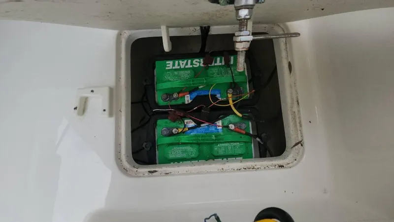 Slide: The Image of Battery compartment of a 2020 Robalo 246 Cayman boat, featuring two green batteries. - 29