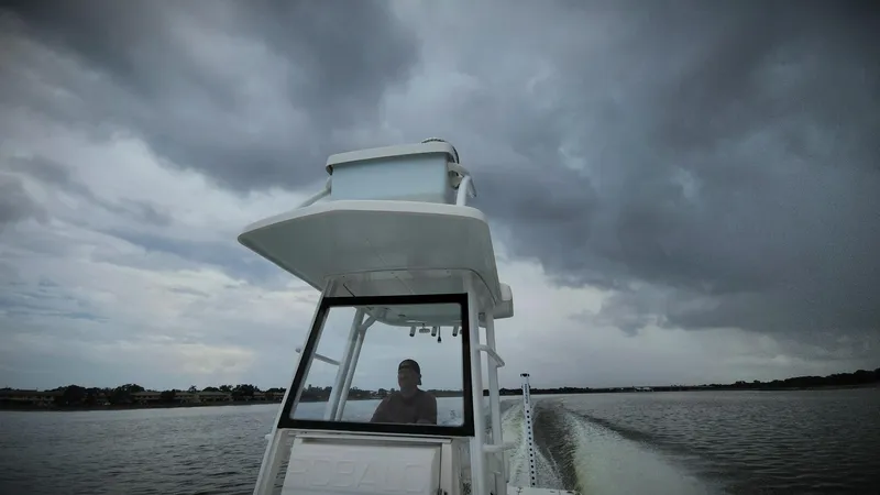Slide: The Image of 2020 Robalo 246 Cayman boat navigating under stormy skies on a calm waterway. - 3