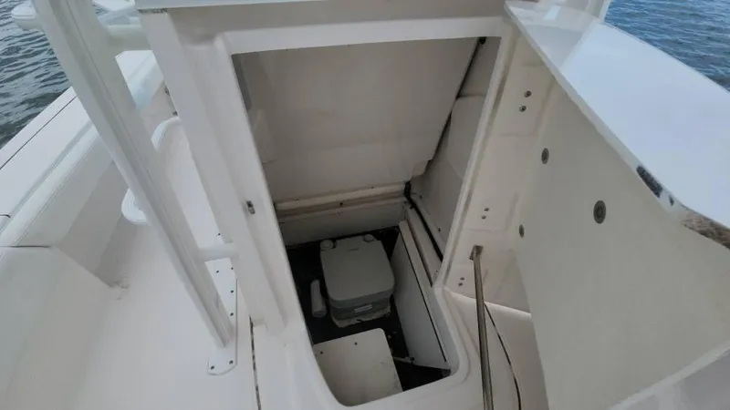 Slide: The Image of 2020 Robalo 246 Cayman boat storage compartment with portable toilet, open view. - 33