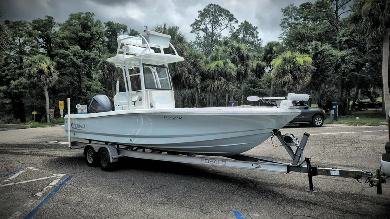 Slide: The Image of 2020 Robalo 246 Cayman boat on trailer in a parking lot with trees in background. - 6