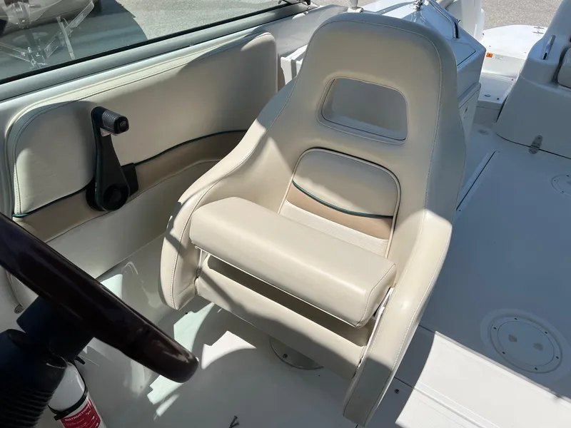 Slide: The Image of Captain's seat on 2000 Chris-Craft 260DB boat, featuring beige upholstery and steering wheel. - 13